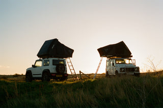 Land rover Defender camper parked in a field at sunset